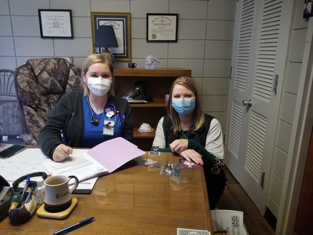 Two women wearing face masks sitting in office at a desk
